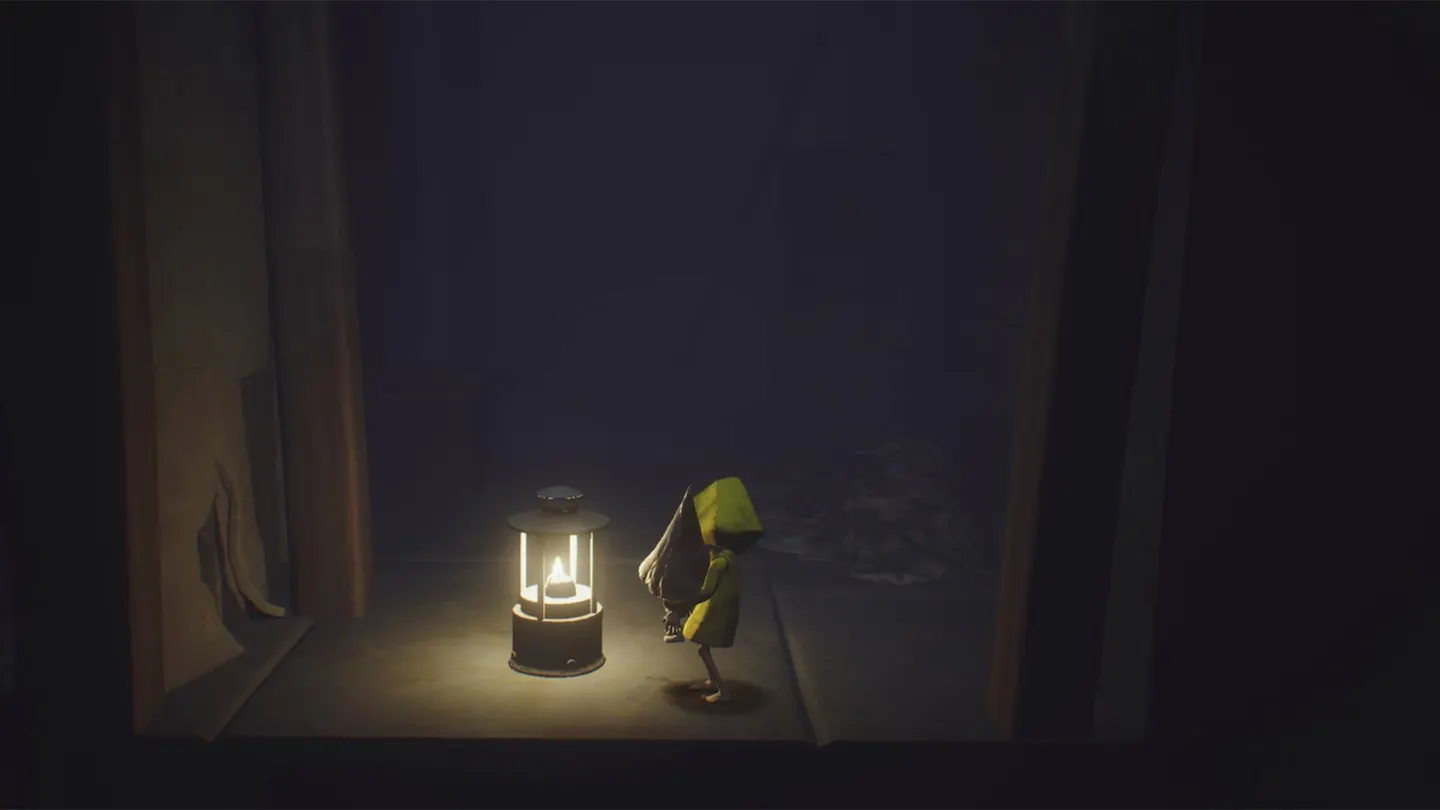 Little Nightmares: Шестая в желтом дождевике обнимает нома в остроконечном колпаке рядом с горящим фонарем в темной комнате